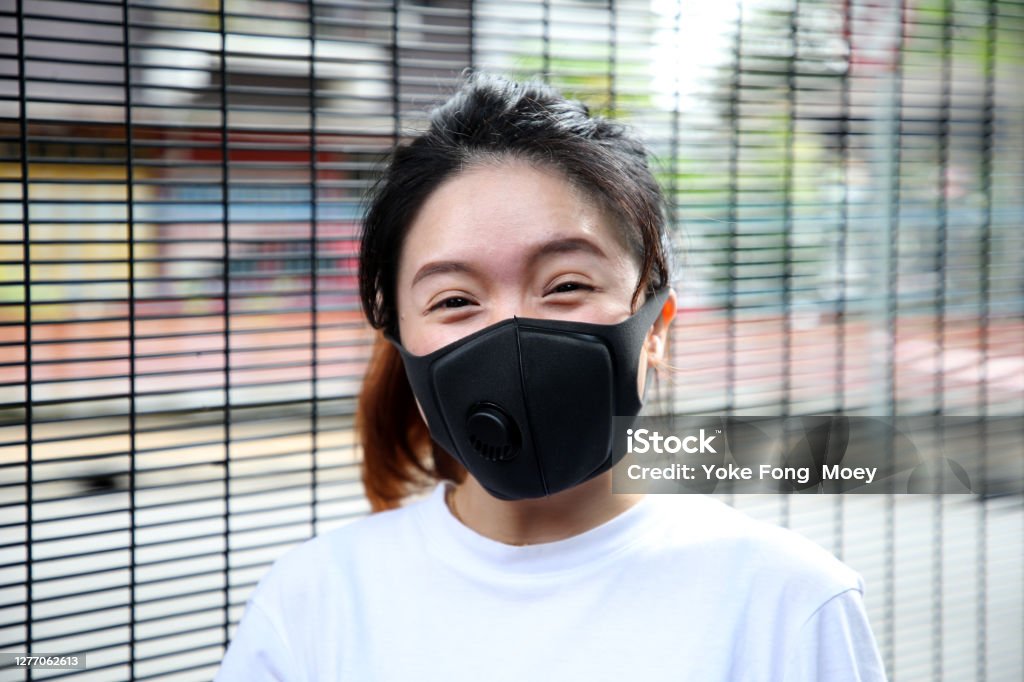 Mask is A New Norm A Chinese female adult is putting on reusable face mask during outdoor moments. 25-29 Years Stock Photo