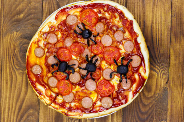 istock Halloween pizza with spiders on wooden table. Top view 1277064269