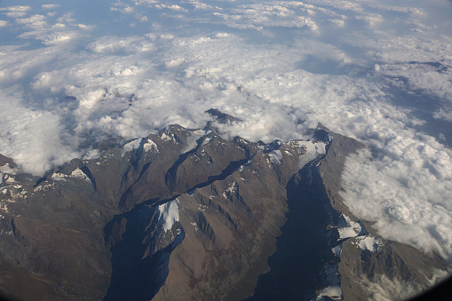 Top view of the mountain peaks of the Alps, covered by clouds and snow.