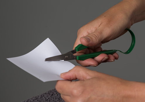 A close up of a hand cutting a piece of paper at a physiotherapist office. Using scissors is a special exercise.