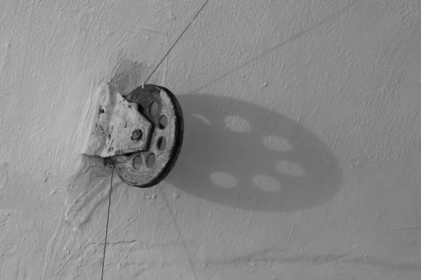 istock Old wheel with a cable, attached to the wall, black and white 1277074209