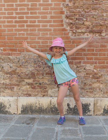 Young girl standing in front of a brick wall