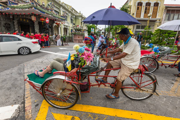 George Town, Penang, Malaysia - December 1, 2019: Street life of Trishaw driver or rickshaws in George Town, Penang, Malaysia in cloudy weather. It is now a part of the city's living heritage.