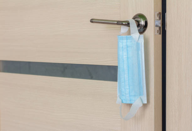 istock A protective surgical mask hangs on the door handle.Protection from viruses and infections when leaving the house and entering public places. 1277082069