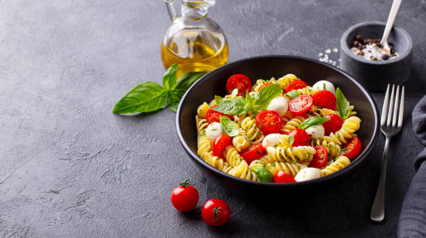 istock Pasta fusilli with mozzarella cheese, tomatoes and basil. Gray background. Copy space. 1277088840