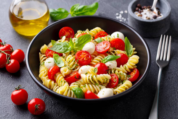 istock Pasta fusilli with mozzarella cheese, tomatoes and basil. Grey background. Close up. 1277088937