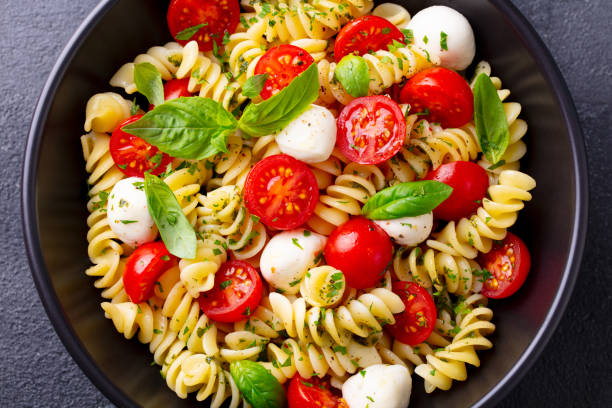istock Pasta fusilli with mozzarella cheese, tomatoes and basil. Grey background. Close up. 1277089024