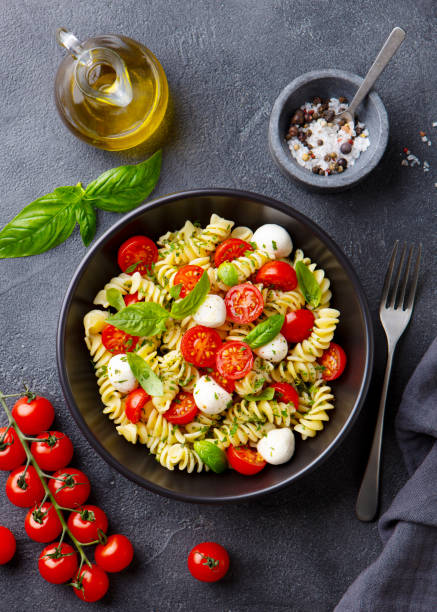 istock Pasta fusilli with mozzarella cheese, tomatoes and basil. Grey background. Top view. 1277089100