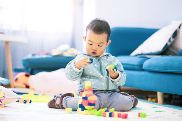 istock Baby boy sitting on the floor playing with building blocks 1277090687