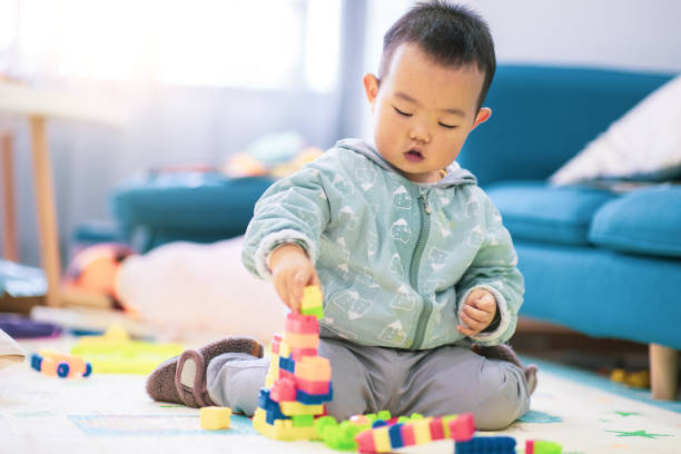 istock Baby boy sitting on the floor playing with building blocks 1277090689