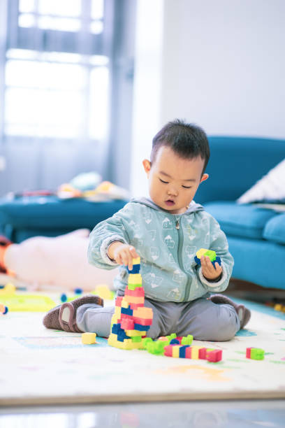 istock Baby boy sitting on the floor playing with building blocks 1277090711