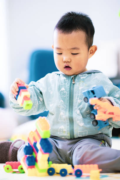 istock Baby boy sitting on the floor playing with building blocks 1277090716