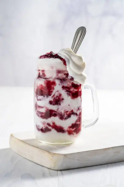 Raspberries yogurt smoothie overflow on a white cutting board table