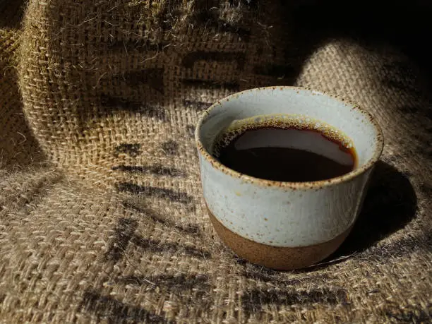 Hot Coffee in Traditional Ceramic Cup on Vintage Coffee Beans Sack