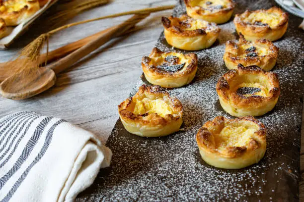fresh and homemade baked puff pastry tartlets with a delicious sour cream filling served on a wooden rustic board
