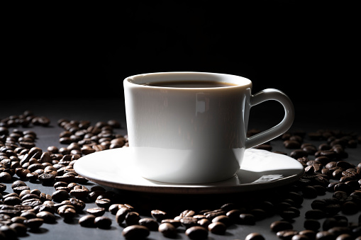 Coffee cup with coffee beans on dark black background