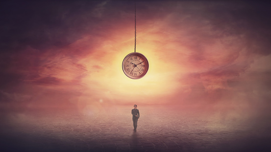 Surreal scene as confident businesswoman stands on the in front of a huge clock hanging from the sunset sky. Time travel concept, achieving success. The importance of time in the modern world.