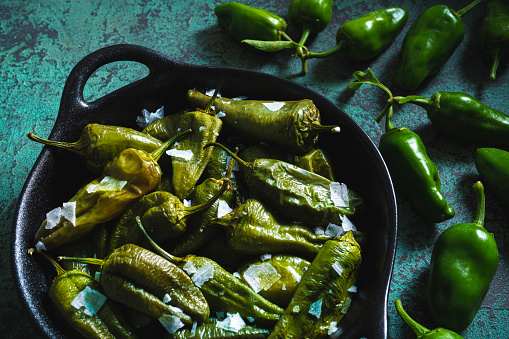 Pimientos del Padron tapas with Spain chili peppers vegan food on green background