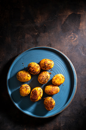 Steamed potatoes after grilled with herbs on blue rustic plate and wooden vintage table