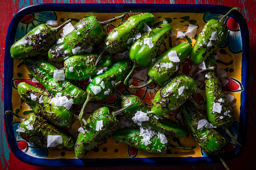 Pimientos del Padron tapas salted are Spain chili peppers vegan food on green background