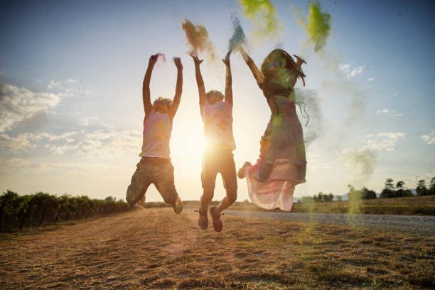 Kids enjoying playing with colourful holi powder. The kids are jumping in the air and throwing the powder.\nNikon D850