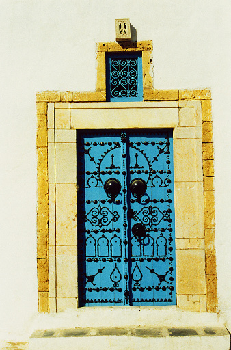 Red roses adorn a turquoise window frame on an adobe structure in old town Albuquerque New Mexico.