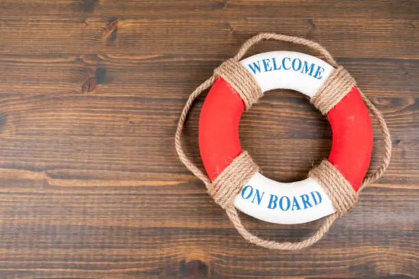 WELCOME ON BOARD. Career, education and teamwork concept. Lifebuoy with text on wooden background