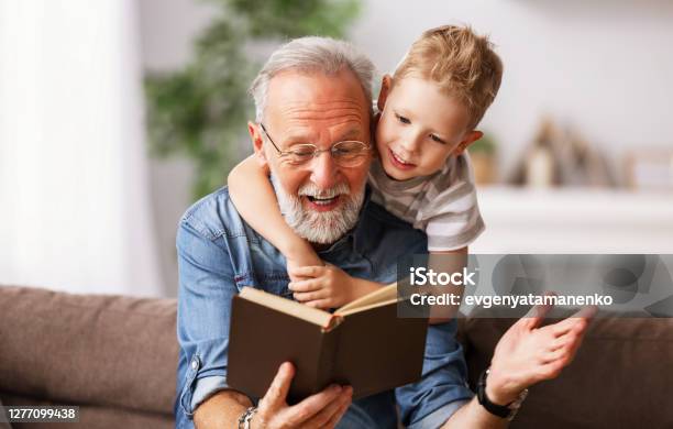 Cheerful Grandfather And Grandson Reading Book Together Stock Photo - Download Image Now