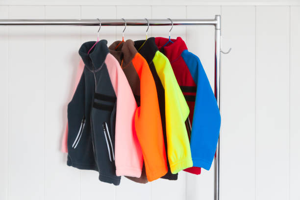 colorful fleece jackets are on a rack near wall - velo casaco imagens e fotografias de stock