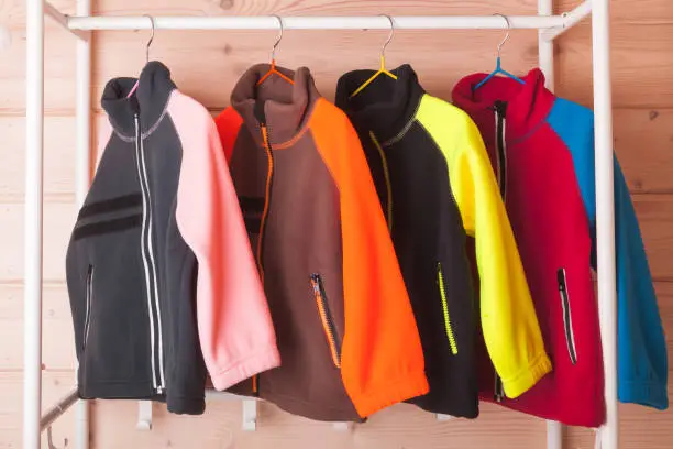 Photo of Colorful fleece jackets are hanging on hangers