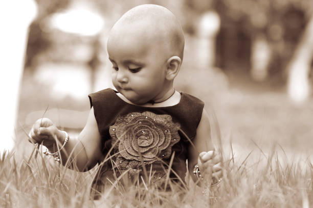 Baby girl playing in green grass outdoors in the nature.