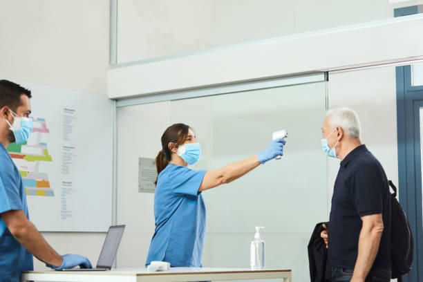 istock Female Nurse Checking Man's Temperature At Counter 1277102641