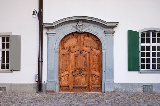 Cobblestone street, old decorative wooden door, an entrance to historical building. Old town in Basel, Switzerland.