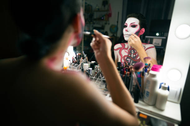 istock Beautiful woman looking herself at make-up mirror and applying make-up for a Halloween party 1277104792