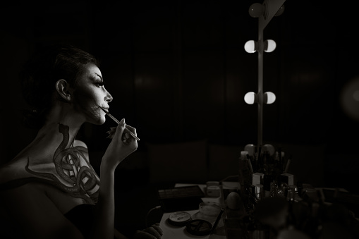 Portrait of a woman applying make-up for the Halloween. Black and white image