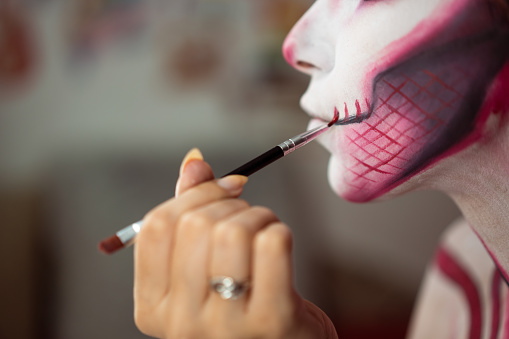 Close-up of an unrecognizable woman's face while applying Halloween make-up