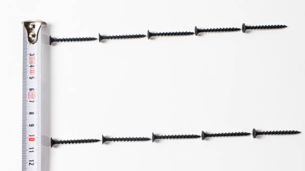 istock Black self-tapping screw and measuring roulette on a white background banner with space for text. Construction tools, fastening hardware. 1277105637