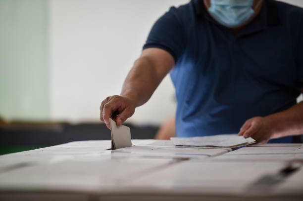 Unrecognizable person casting a vote into the ballot box during corona virus pandemic stock photo