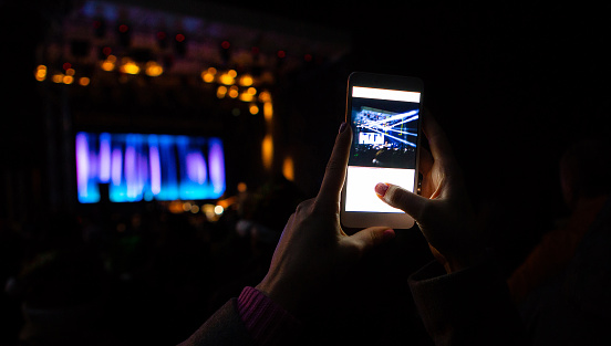 Woman is taking pictures of a street concert on the smartphone