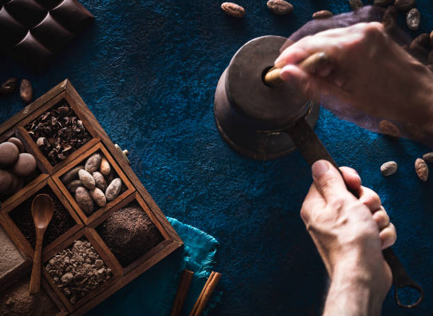 Chocolate pot copper grinding cocoa with hands holding stick with assorted chocolate box with drops cocoa powder and chocolate beans