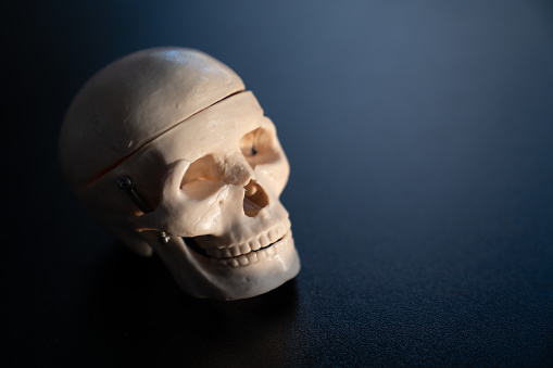 Spooky photo of human skull in dark. The background is black. Shot with a full frame mirrorless camera.
