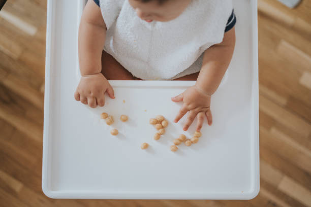 Happy baby sitting at table eating chickpeas