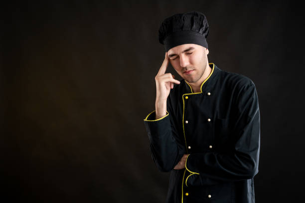 istock Young male dressed in a black chef suit has headache 1277110651