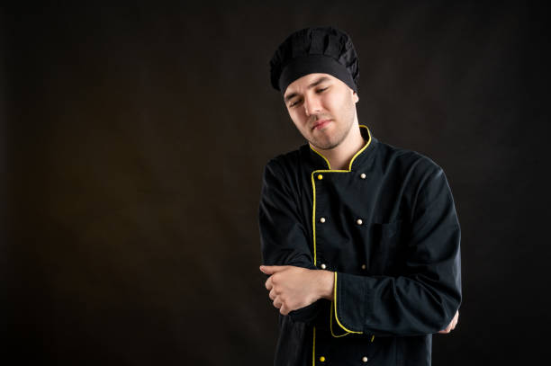 istock Young male dressed in a black chef suit has elbow pain 1277110835
