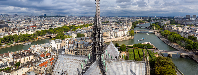 Paris, 75004, France - August 8, 2017: Notre Dame de Paris Cathedral roof with its spire by architect Viollet-Le-Duc. The view includes Ile Saint-Louis and Seine River banks (UNESCO World Heritage)