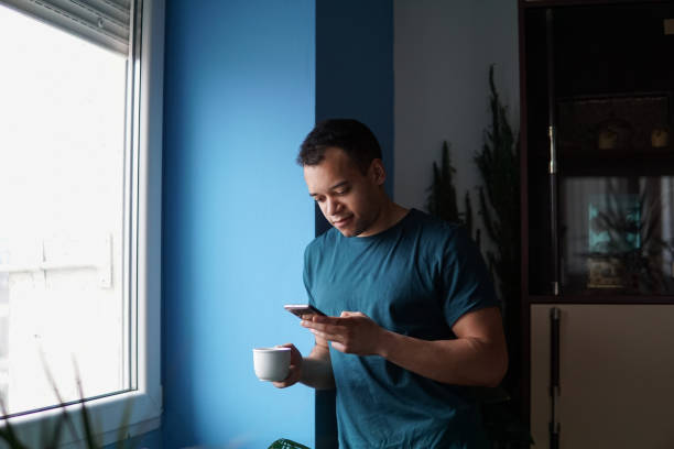 istock Man using a phone at home while drinking coffee in the morning 1277112110