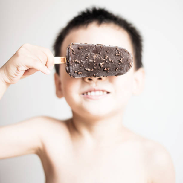 Little kid holding a chocolate Popsicle on white background