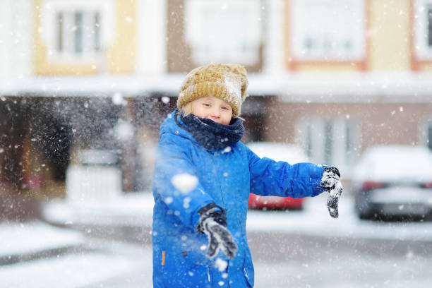 kleiner junge mit spaß spielen mit neuschnee. schneeballkampf. aktive freizeit für kinder am verschneiten wintertag. - 11084 stock-fotos und bilder