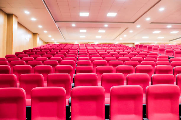 istock empty seats of an auditorium with red reclining rows of seats and false ceiling led lights. 1277113136
