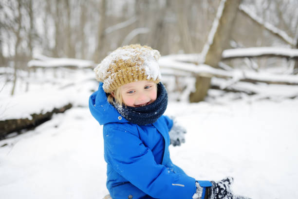 ragazzino che si diverte a giocare con la neve fresca. tempo libero attivo all'aperto per i bambini nella giornata invernale innevata. - 11088 foto e immagini stock